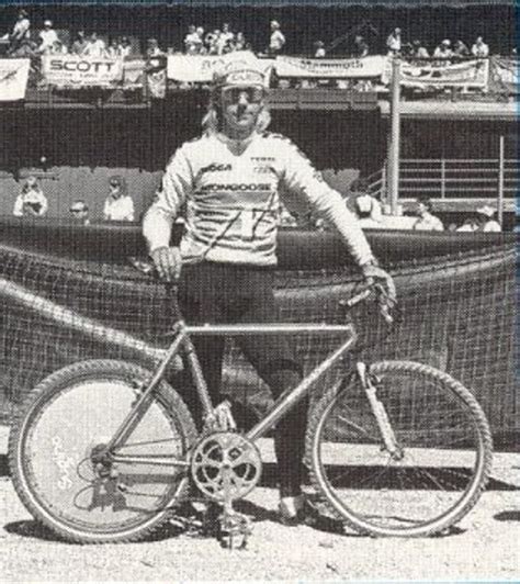 A Man Standing Next To His Bike In Front Of A Boat