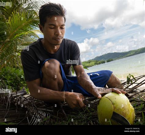 Portrait Of Young Asian Fisherman Opening A Coconut On A Tropical