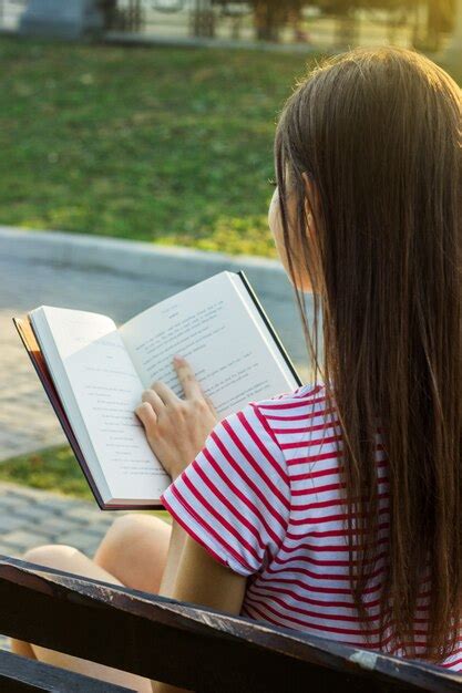 Vista Posterior De Una Mujer Joven Que Lee Un Libro Y Se Relaja En El