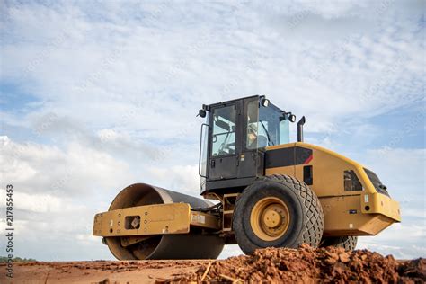 Yellow vibratory soil compactor working on highway construction site ...