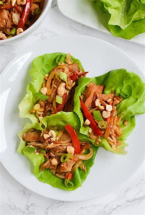 Lettuce Wraps Filled With Meat And Vegetables On A Plate Next To A Bowl