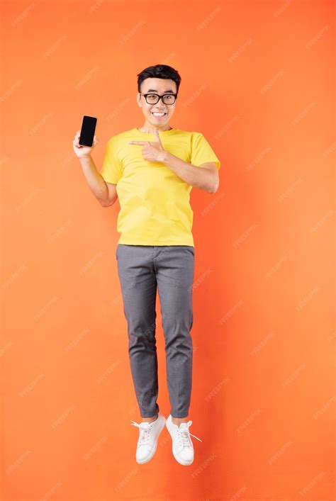 Premium Photo Asian Man In Yellow T Shirt Jumping On Orange Wall