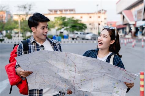 Mochileiros de turista feliz casal asiático segurando o mapa de papel e