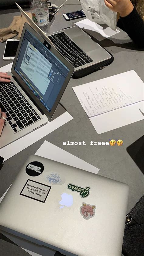 Two People Sitting At A Table With Laptops And Papers In Front Of Them