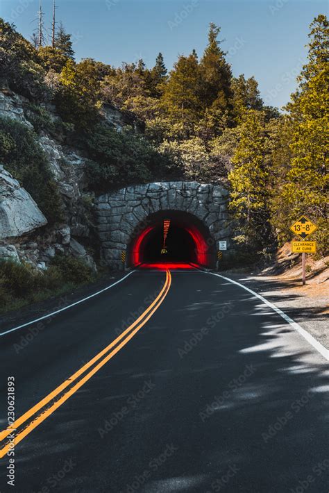 highway road, yellow double line leads to a tunnel with red light inside Stock Photo | Adobe Stock