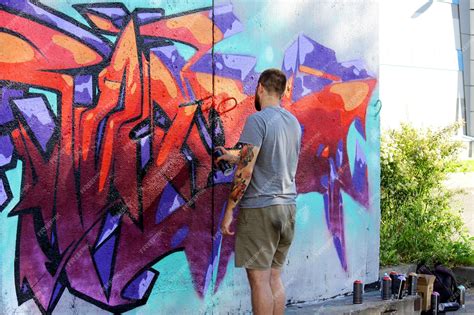 Premium Photo | A street artist paints colored graffiti on the wall of ...