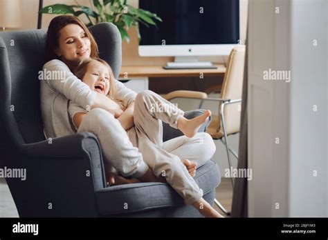 Beautiful Mother With A 3 Year Old Daughter Sit In A Gray Armchair Hug