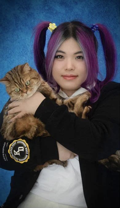 A Woman With Purple Hair Holding A Cat