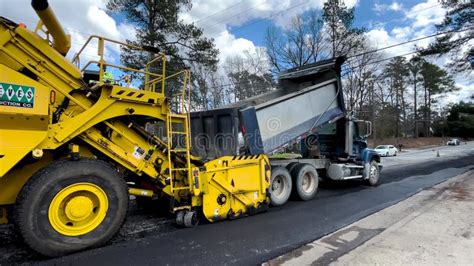 Road Paving Crew Dump Truck Dumping Hot Asphalt Into A Road Paver