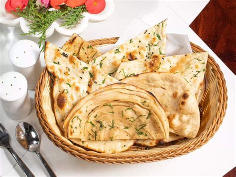 Some Pita Bread Is In A Wicker Basket On A Table With Silverware