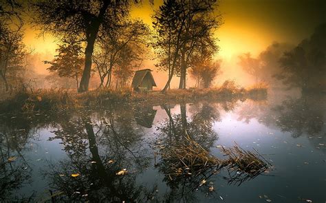 Reflection Of Brown House Between Trees On Body Of Water Lake Mist