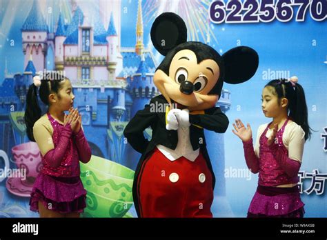 Mickey Mouse Poses Between Two Young Girls At A Press Conference For