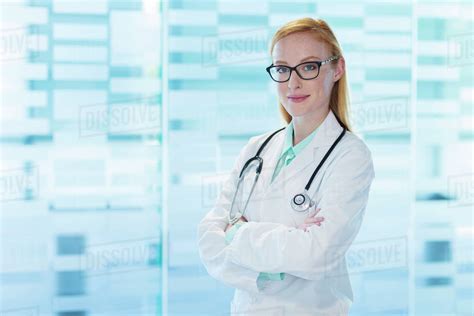 Portrait Of Smiling Female Doctor Wearing Glasses And Lab Coat Standing