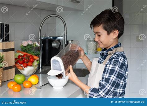 A Teenager Schoolboy Prepares Breakfast For Himself Pours Cereal Into A