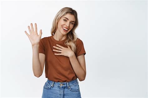 Free Photo Smiling Friendly Woman Raising Hand And Hold Arm On Heart