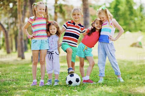 Group of little friends playing football in the park - Stock Photo - Dissolve