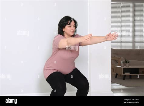 Overweight Mature Woman Squatting Near Wall At Home Stock Photo Alamy
