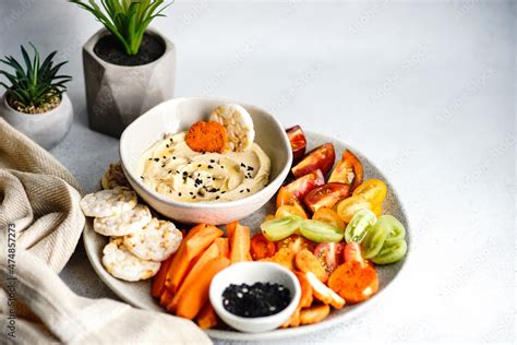 Hummus and vegetables crudites with rice crackers and sunflower seeds Stock Photo | Adobe Stock