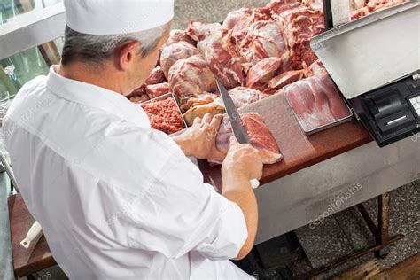 Carnicero masculino cortando carne en el gabinete de exhibición Foto