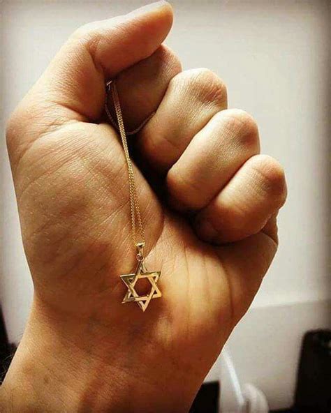 A Hand Holding A Gold Star Of David Necklace