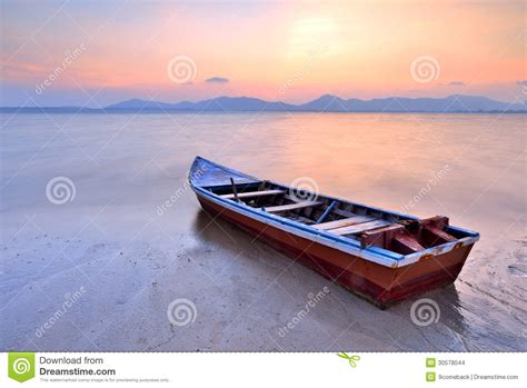 Thai Longtail Boat In The Sea At Sunset With Big Red Sun And Mountains