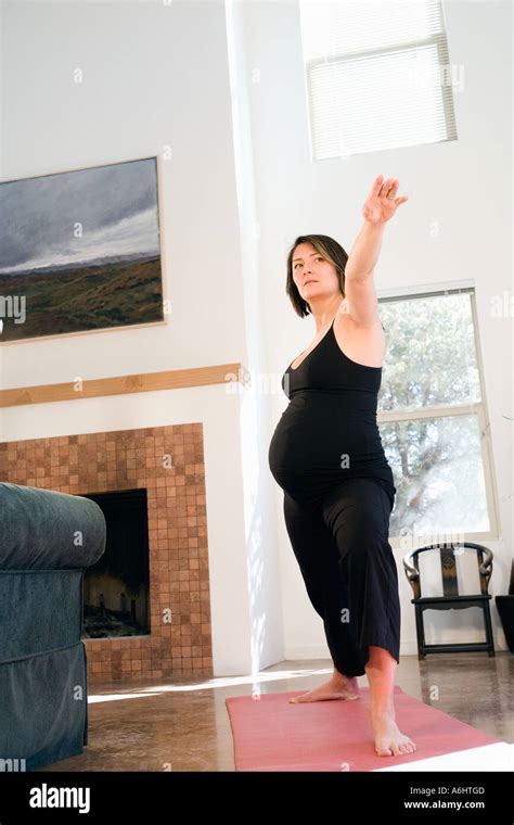 Pregnant Asian American Woman Doing Stretching Exercise At Home Stock