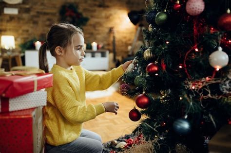 Menina Decorando A árvore De Natal Na Sala De Estar Foto Grátis