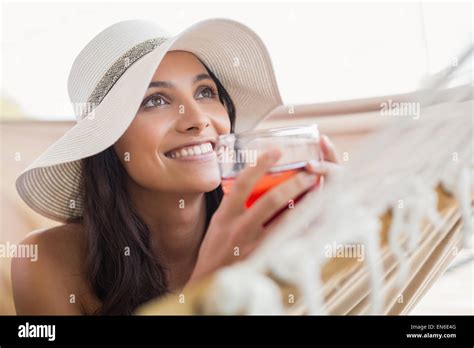 Pretty Brunette Relaxing On A Hammock And Drinking Cocktail Stock Photo