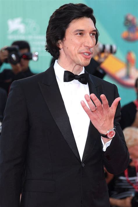 A Man In A Tuxedo And Bow Tie Making A Hand Gesture At An Event