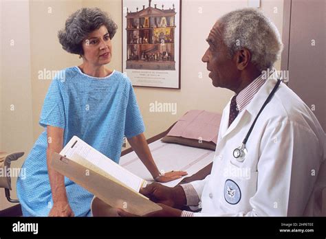 An African American Male Doctor Consults With An Adult Female Patient