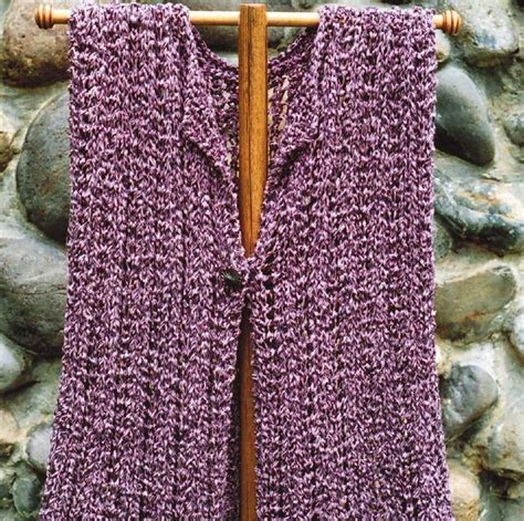 A Purple Knitted Vest Hanging On A Wooden Hanger Next To A Stone Wall