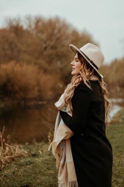 Premium Photo Woman In Black Coat And White Sun Hat Standing On Green