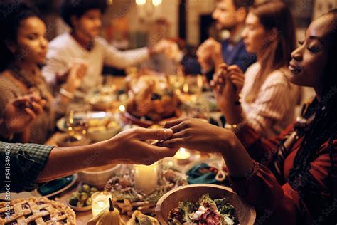 Close Up Of Couple Holding Hands While Praying With Friends During