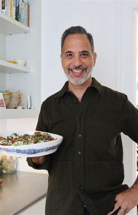 A Man Holding A Plate With Food On It In His Hand And Smiling At The Camera