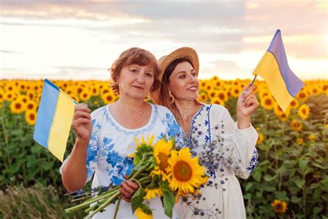 Women Hold Ukrainian Flags In Sunflower Summer Field At Sunset