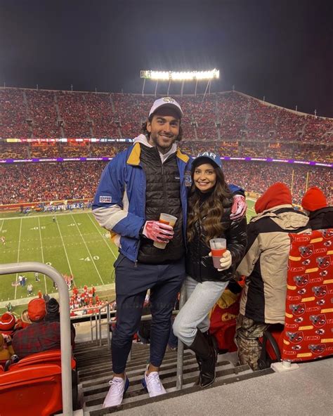 A Man And Woman Standing On The Sidelines At A Football Stadium With