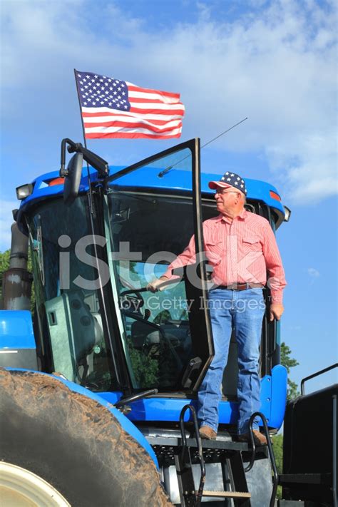 Patriotic American Farmer Standing On Tractor With Flag Stock Photo