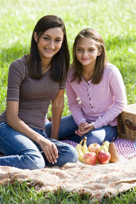 Filles S Asseyant Sur La Couverture De Pique Nique Sur L Herbe En