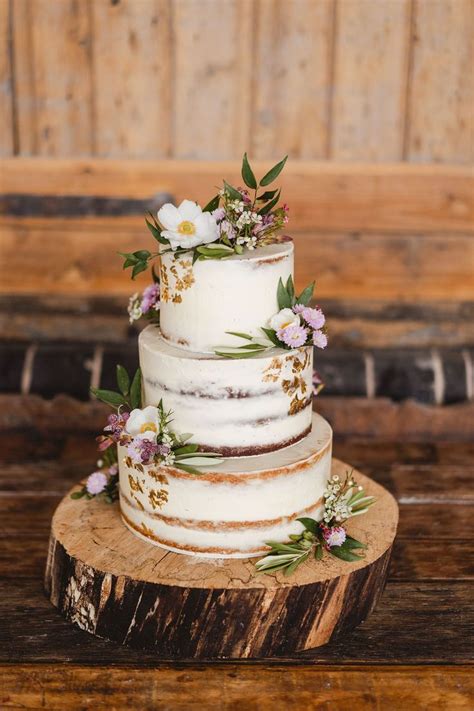 Rustic Semi Naked Wedding Cake With Flowers And Buttercream On A Log