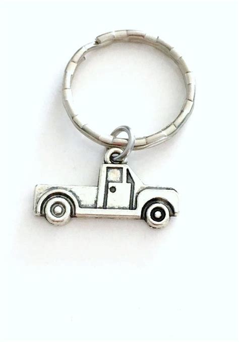 A Metal Keychain With A Small Truck On Its Front And Side