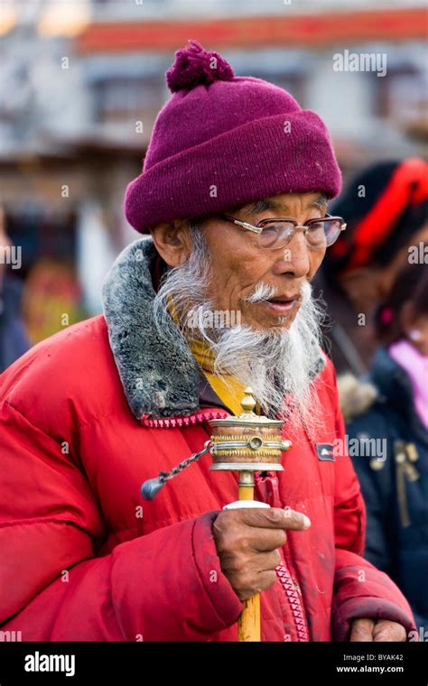 Old Tibetan Man Pilgrim With White Beard And Moustache Spinning Prayer