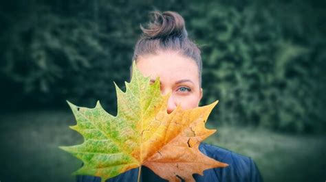 Premium Photo Portrait Of Woman Holding Maple Leaf Outdoors