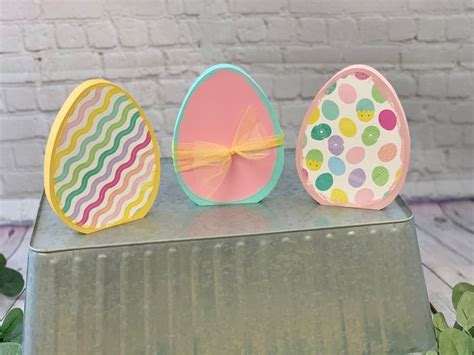 Three Decorated Easter Eggs Sitting On Top Of A Table