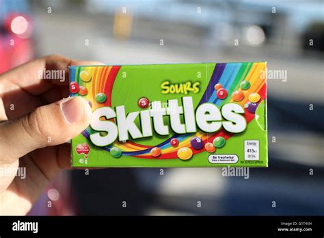 Close Up Of Hand Holding Box Of Sour Skittles Sweets In Green Packaging