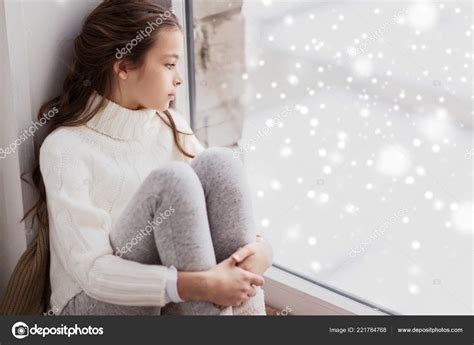 Sad Girl Sitting On Sill At Home Window In Winter Stock Photo By Syda