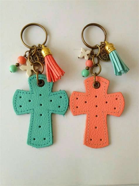 Two Cross Shaped Key Chains With Tassels On Them