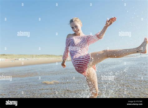 Netherlands Young Woman Splashing Water At The Beach In Summer Stock