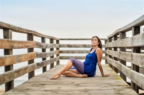 Una Mujer Joven Sentada En La Pasarela De Madera Que Conduce A La Playa