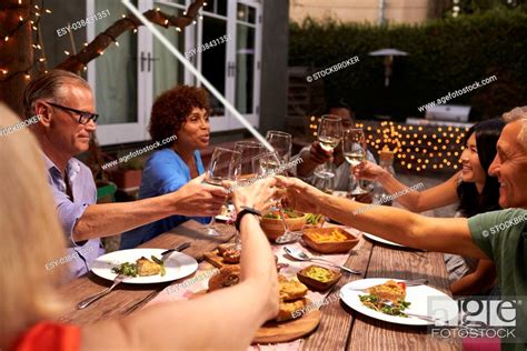 Group Of Mature Friends Enjoying Outdoor Meal In Backyard Stock Photo