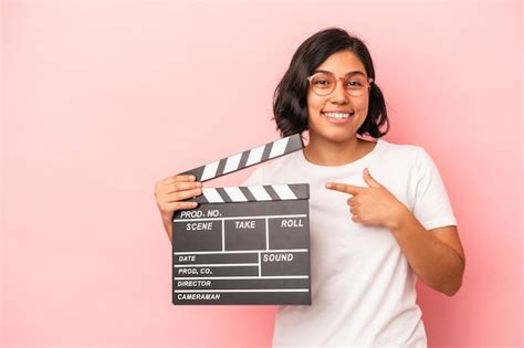 Jovem Mulher Latina Segurando Claquete Isolada No Fundo Rosa Sorrindo E Apontando De Lado